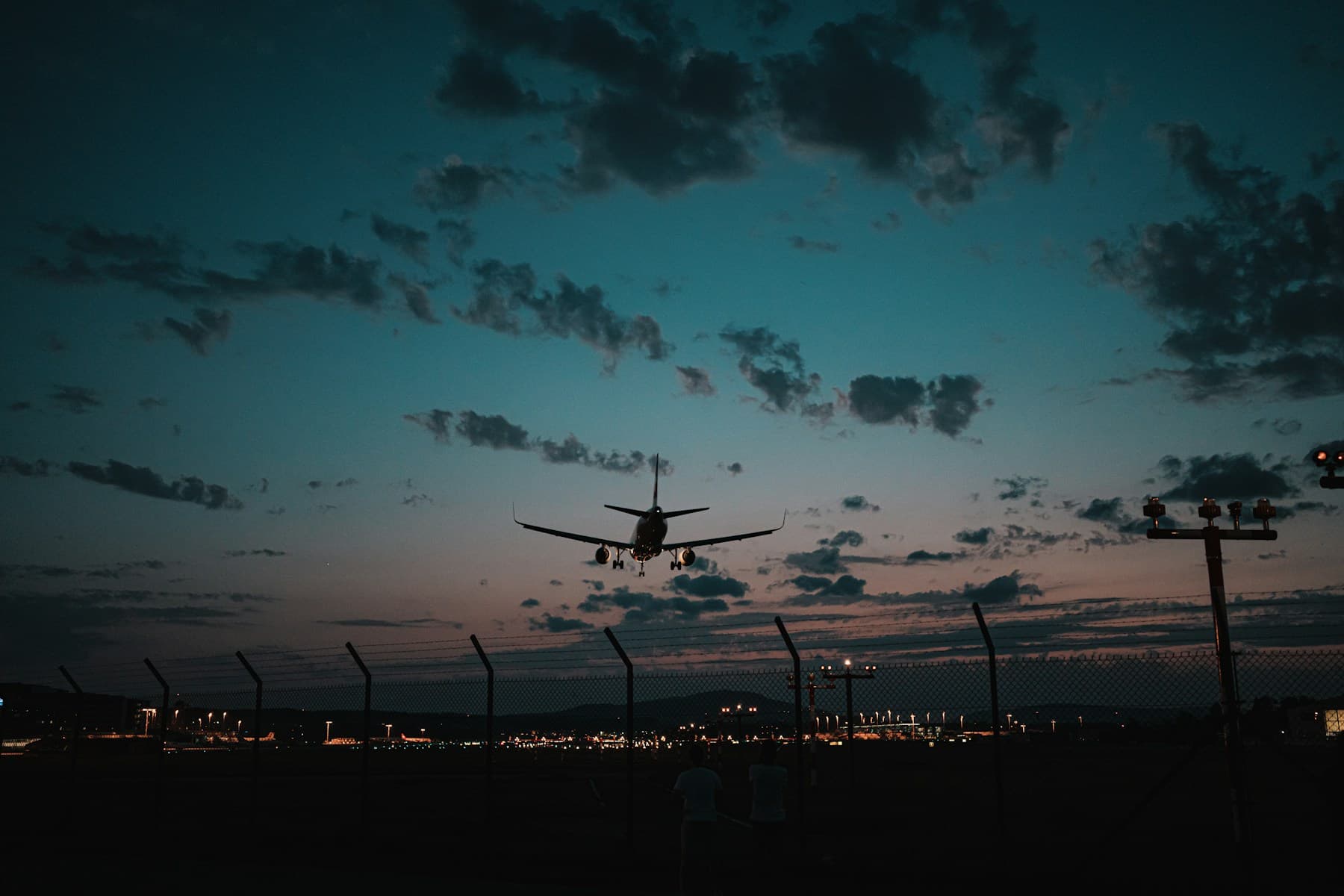 An aircraft coming in to land over airport lights at dusk